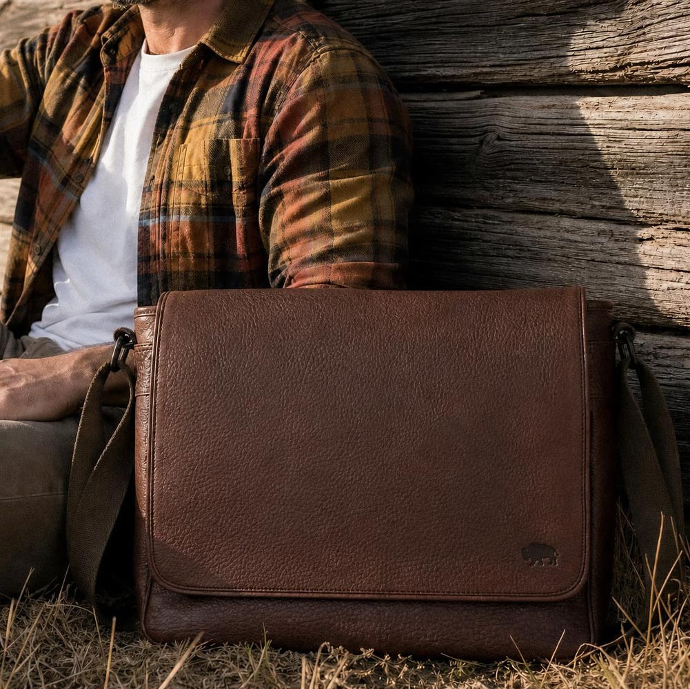 Roosevelt Buffalo Leather Messenger Bag in a rustic outdoor setting — rich dark brown patina